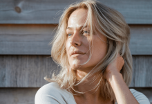 Женщина смотрит в сторону на фоне забора