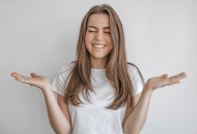 Дівчина ніяково радіє та розводить руки