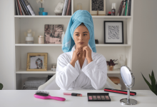 Дівчина з рушником на голові сидить за столом