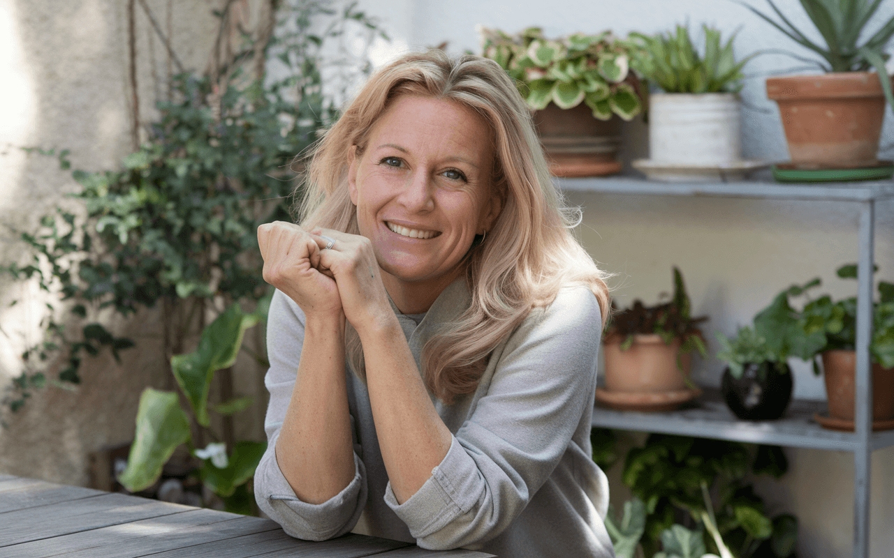 Жінка склала руки поруч з обличчям і сидить за столом