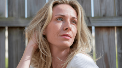 Жінка сидить на фоні паркана