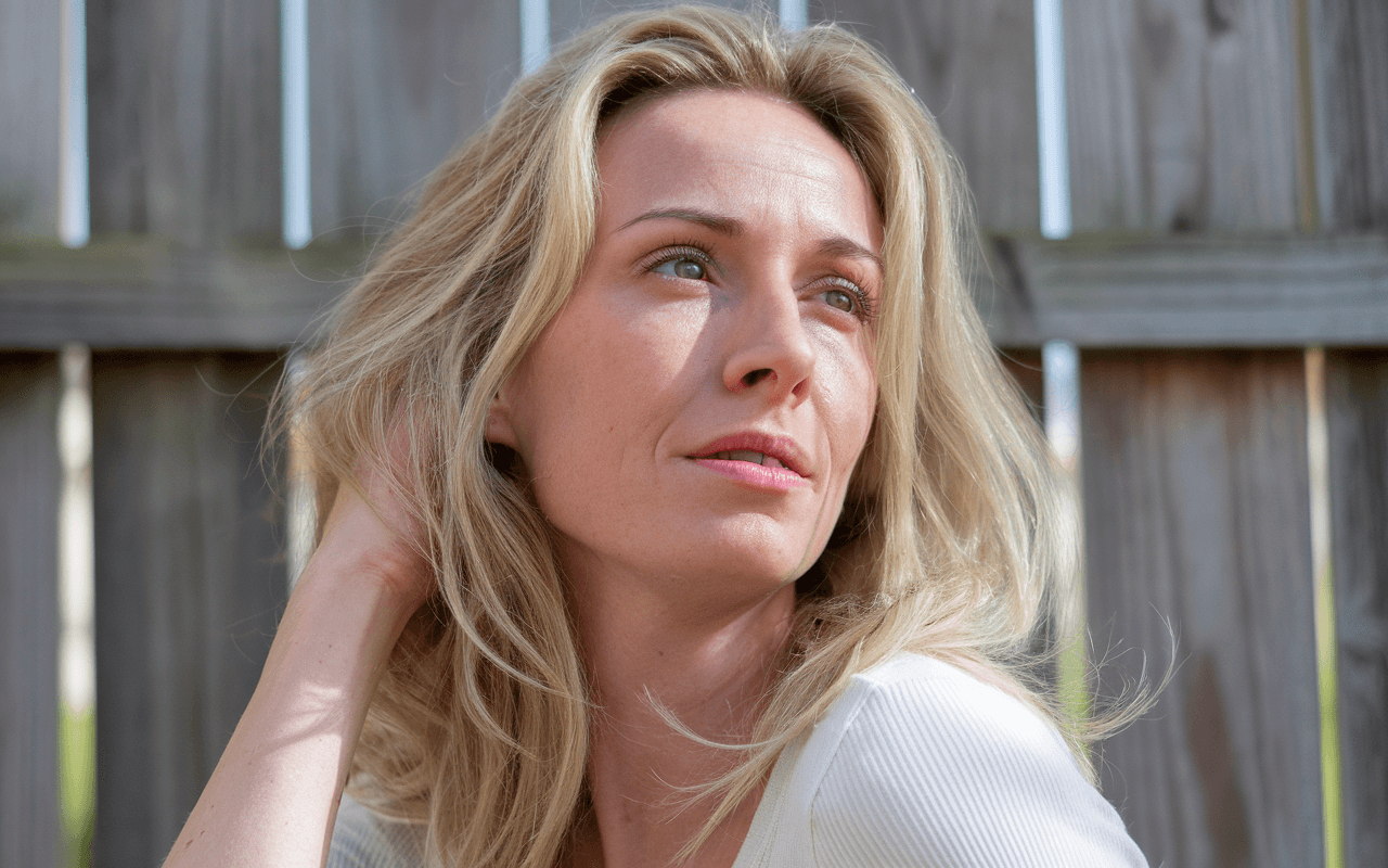 Жінка сидить на фоні паркана