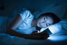 Дівчина лежить і дивиться в телефон