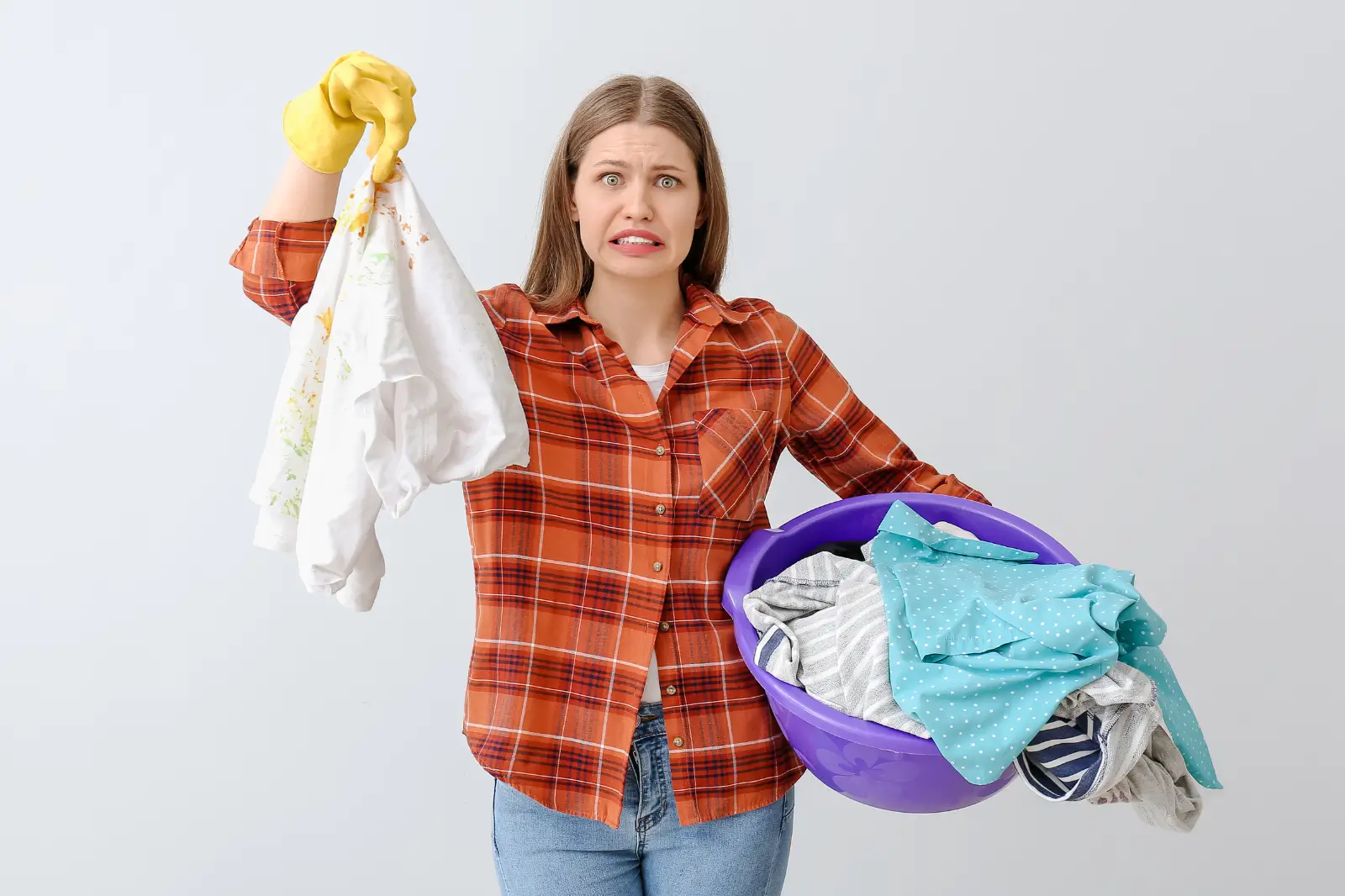 ДЕвушка держит в руках грязную одежду