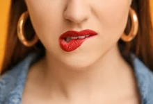 Девушка кусает губы с красной помадой