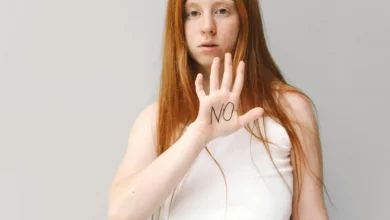 девушка выставляет руку и на ладони написано "NO"